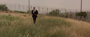 Movie still from “Paradise Now” (2005), directed by Hany Abu-Assad – A man in a suit and tie walking through a grassy field; Extreme Wide shot, Low angle