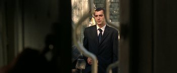 Movie still from “Paradise Now” (2005), directed by Hany Abu-Assad – A man wearing a suit and tie standing in front of a brick wall; Medium shot, Low angle