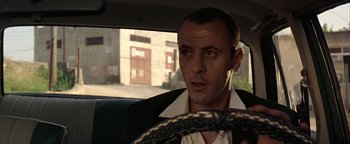 Movie still from “Paradise Now” (2005), directed by Hany Abu-Assad – A man in a suit driving a car in the street; Close Up shot, Low angle