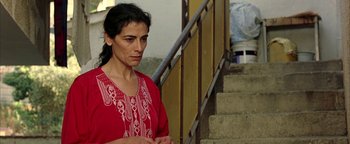 Movie still from “Paradise Now” (2005), directed by Hany Abu-Assad – A woman in a red shirt standing next to a staircase; Close Up shot, Low angle