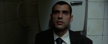 Movie still from “Paradise Now” (2005), directed by Hany Abu-Assad – A man wearing a suit and tie in front of a refrigerator; Close Up shot, Low angle
