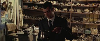 Movie still from “Paradise Now” (2005), directed by Hany Abu-Assad – A man in a suit and tie pouring something from a coffee pot; Medium shot, Low angle