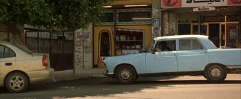 Movie still from “Paradise Now” (2005), directed by Hany Abu-Assad – An old car is parked on the side of the road; Wide shot, Low angle