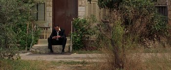 Movie still from “Paradise Now” (2005), directed by Hany Abu-Assad – A man in a suit sitting on the steps of a house; Wide shot, High angle