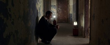 Movie still from “Paradise Now” (2005), directed by Hany Abu-Assad – A man sitting in a dark room looking at his cell phone; Wide shot, Low angle