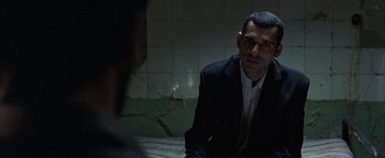 Movie still from “Paradise Now” (2005), directed by Hany Abu-Assad – A man in a suit sitting on a bed in front of a tiled wall; Close Up shot, Over the shoulder angle