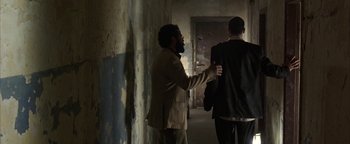 Movie still from “Paradise Now” (2005), directed by Hany Abu-Assad – Two men are walking down a hallway in a building; Medium shot, Over the shoulder angle