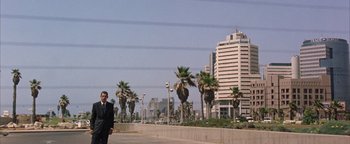 Movie still from “Paradise Now” (2005), directed by Hany Abu-Assad – A man in a suit standing next to palm trees; Extreme Wide shot, Low angle