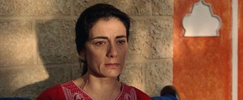 Movie still from “Paradise Now” (2005), directed by Hany Abu-Assad – A person wearing a red shirt near a brick wall; Close Up shot, High angle