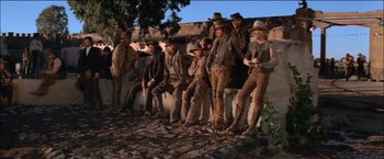 Movie still from “Pat Garrett & Billy the Kid” (1973), directed by Sam Peckinpah – A group of men standing next to each other on a wall; Wide shot, Low angle
