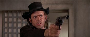 Movie still from “Pat Garrett & Billy the Kid” (1973), directed by Sam Peckinpah – A man in a black hat is pointing a gun; Close Up shot, Low angle