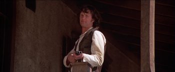 Movie still from “Pat Garrett & Billy the Kid” (1973), directed by Sam Peckinpah – A man holding a gun while wearing a vest; Medium shot, Low angle
