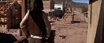 Movie still from “Pat Garrett & Billy the Kid” (1973), directed by Sam Peckinpah – A man standing in the middle of a dirt road; Wide shot, Low angle