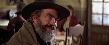 Movie still from “Pat Garrett & Billy the Kid” (1973), directed by Sam Peckinpah – An old man with a beard and a hat; Close Up shot, Over the shoulder angle