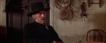 Movie still from “Pat Garrett & Billy the Kid” (1973), directed by Sam Peckinpah – A man wearing a black hat and a black suit; Close Up shot, Low angle
