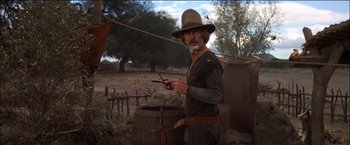 Movie still from “Pat Garrett & Billy the Kid” (1973), directed by Sam Peckinpah – An old man in a cowboy hat is holding a cell phone; Medium shot, Low angle