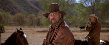 Movie still from “Pat Garrett & Billy the Kid” (1973), directed by Sam Peckinpah – A man wearing a brown hat and a brown jacket; Medium shot, Low angle