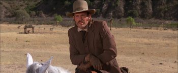 Movie still from “Pat Garrett & Billy the Kid” (1973), directed by Sam Peckinpah – A man in a suit and hat sitting on top of a horse in a field; Medium shot, Low angle