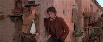 Movie still from “Pat Garrett & Billy the Kid” (1973), directed by Sam Peckinpah – A man in a brown jacket and a man in a black hat; Medium shot, Over the shoulder angle