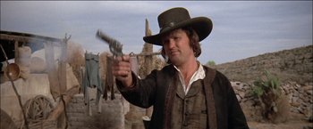 Movie still from “Pat Garrett & Billy the Kid” (1973), directed by Sam Peckinpah – A man in a cowboy hat holding a gun in his hand; Close Up shot, Low angle