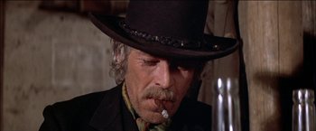 Movie still from “Pat Garrett & Billy the Kid” (1973), directed by Sam Peckinpah – An older man wearing a hat and smoking a cigarette; Close Up shot, Low angle