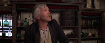 Movie still from “Pat Garrett & Billy the Kid” (1973), directed by Sam Peckinpah – An older man sitting in front of a wooden wall; Close Up shot, Low angle