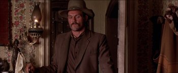 Movie still from “Pat Garrett & Billy the Kid” (1973), directed by Sam Peckinpah – A man wearing a brown suit and a brown hat; Medium shot, Low angle
