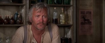 Movie still from “Pat Garrett & Billy the Kid” (1973), directed by Sam Peckinpah – An older man sitting in front of a shelf with bottles; Close Up shot, Low angle