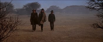Movie still from “Pat Garrett & Billy the Kid” (1973), directed by Sam Peckinpah – A group of men walking across a dirt field; Wide shot, Low angle