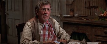 Movie still from “Pat Garrett & Billy the Kid” (1973), directed by Sam Peckinpah – An older man sitting at a table holding a cell phone; Close Up shot, Over the shoulder angle