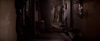 Movie still from “Pat Garrett & Billy the Kid” (1973), directed by Sam Peckinpah – A man standing in a dark room in front of a door; Wide shot, High angle