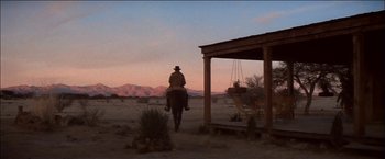 Movie still from “Pat Garrett & Billy the Kid” (1973), directed by Sam Peckinpah – A man riding a horse down a dirt road at sunset; Extreme Wide shot, Low angle