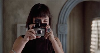 Movie still from “Patty Hearst” (1988), directed by Paul Schrader – A woman taking a picture of herself with a camera; Close Up shot, Low angle