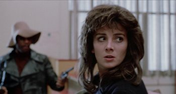 Movie still from “Patty Hearst” (1988), directed by Paul Schrader – A person holding a gun in a room; Close Up shot, Over the shoulder angle