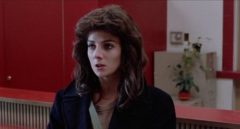 Movie still from “Patty Hearst” (1988), directed by Paul Schrader – A young woman with long brown hair wearing a black jacket; Close Up shot, Over the shoulder angle