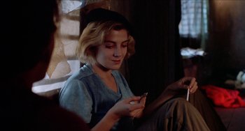 Movie still from “Patty Hearst” (1988), directed by Paul Schrader – A woman sitting in front of a window looking at her cell phone; Close Up shot, Over the shoulder angle