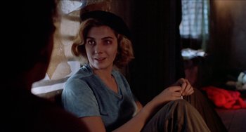 Movie still from “Patty Hearst” (1988), directed by Paul Schrader – A woman sitting on a couch in front of a window; Close Up shot, Over the shoulder angle