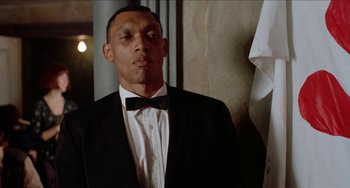 Movie still from “Patty Hearst” (1988), directed by Paul Schrader – A man in a suit and a bow tie; Close Up shot, Low angle