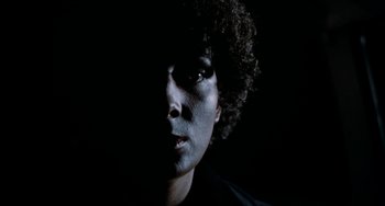 Movie still from “Patty Hearst” (1988), directed by Paul Schrader – A man with a black face and curly black hair; Close Up shot, Low angle