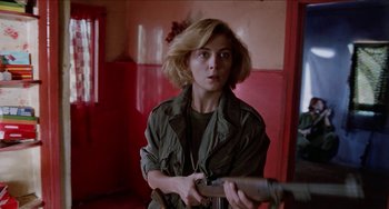 Movie still from “Patty Hearst” (1988), directed by Paul Schrader – A woman holding a gun in a room with red walls; Close Up shot, Low angle