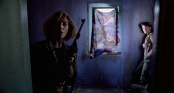 Movie still from “Patty Hearst” (1988), directed by Paul Schrader – A woman holding a gun in front of an open window; Medium shot, Low angle