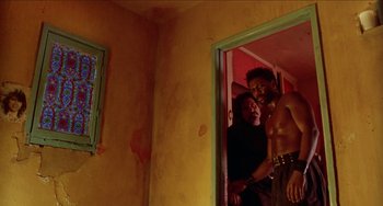 Movie still from “Patty Hearst” (1988), directed by Paul Schrader – A man and a woman standing in front of a door; Medium shot, Low angle