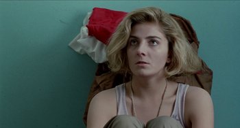 Movie still from “Patty Hearst” (1988), directed by Paul Schrader – A woman sitting on the ground looking at the camera; Close Up shot, Low angle