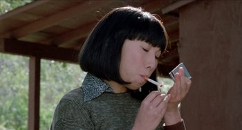 Movie still from “Patty Hearst” (1988), directed by Paul Schrader – A woman smoking a cigarette while holding a cell phone; Close Up shot, Low angle