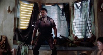 Movie still from “Patty Hearst” (1988), directed by Paul Schrader – A man standing in front of a window; Medium shot, Low angle