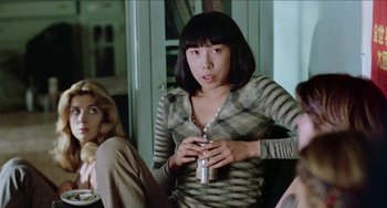 Movie still from “Patty Hearst” (1988), directed by Paul Schrader – A woman sitting on a couch holding a can of soda; Medium shot, Over the shoulder angle