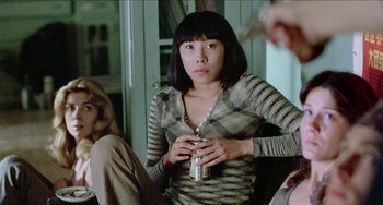 Movie still from “Patty Hearst” (1988), directed by Paul Schrader – A woman holding a can of beer in her hands; Medium shot, Over the shoulder angle