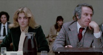 Movie still from “Patty Hearst” (1988), directed by Paul Schrader – A woman and a man sitting at a conference table; Medium shot, Over the shoulder angle