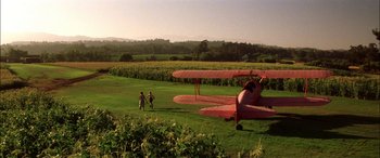 Movie still from “Pearl Harbor” (2001), directed by Michael Bay – Two people are standing in front of an airplane in a field; Extreme Wide shot, High angle