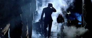 Movie still from “Pearl Harbor” (2001), directed by Michael Bay – A man in a black suit walking through a smoke filled room; Wide shot, Low angle